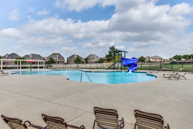 view of swimming pool with a patio, a water slide, and pool water feature