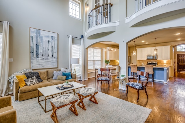 living room with a high ceiling, a wealth of natural light, and dark hardwood / wood-style floors