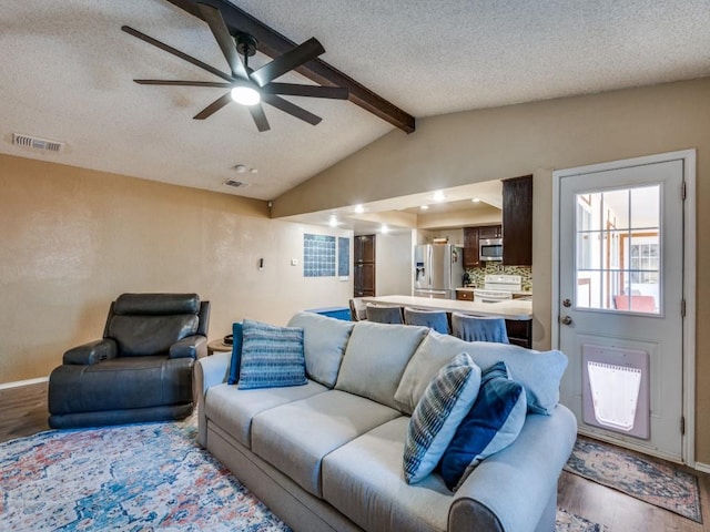 living area with wood finished floors, a ceiling fan, baseboards, and a textured ceiling
