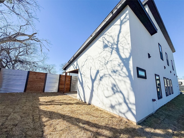 view of side of property with fence and stucco siding