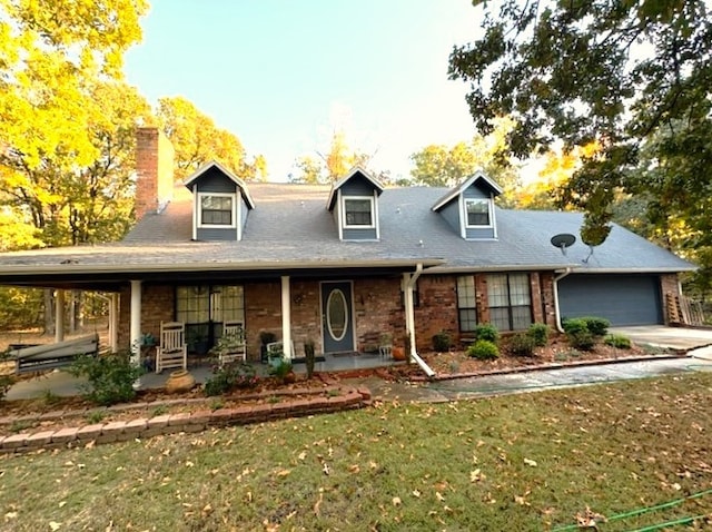 cape cod home with a front lawn, covered porch, and a garage