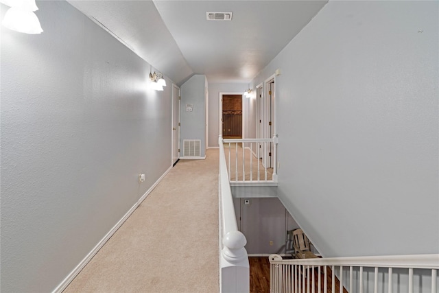 hall featuring vaulted ceiling, carpet floors, visible vents, and baseboards