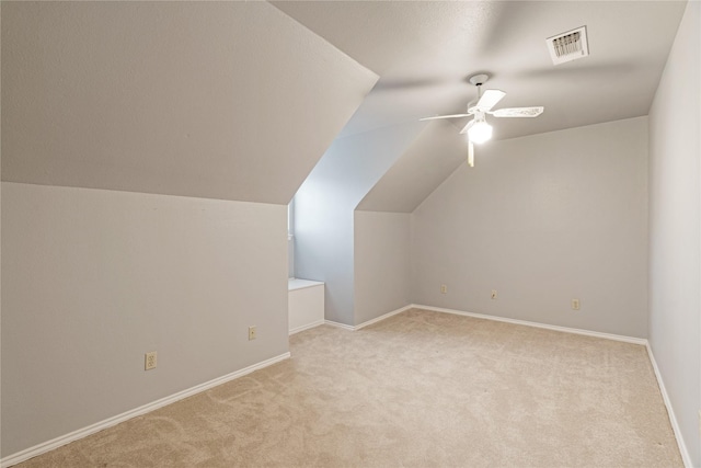 additional living space with carpet flooring, visible vents, baseboards, vaulted ceiling, and a ceiling fan