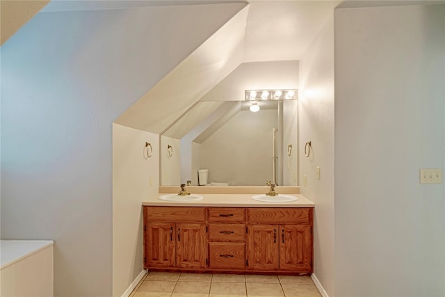 bathroom featuring double vanity, tile patterned flooring, a sink, and baseboards