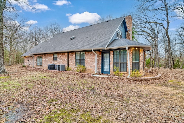 back of property with roof with shingles, cooling unit, and brick siding