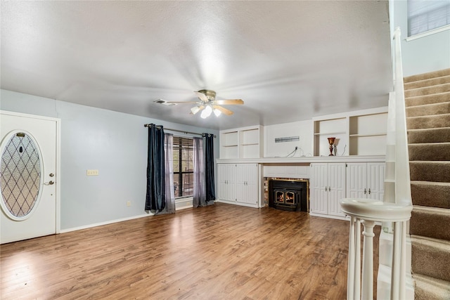 unfurnished living room with baseboards, visible vents, ceiling fan, wood finished floors, and stairs