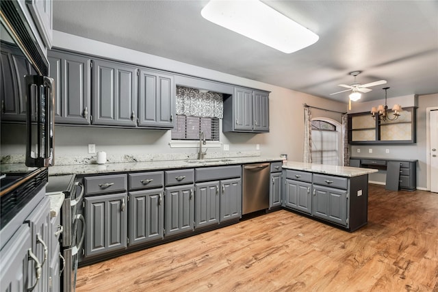 kitchen featuring a peninsula, a sink, stainless steel dishwasher, gray cabinets, and light wood finished floors