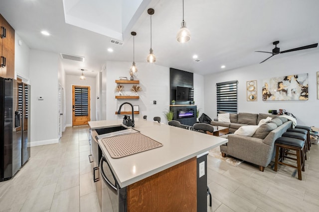 kitchen with ceiling fan, a kitchen island with sink, a breakfast bar, and decorative light fixtures