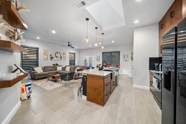 kitchen featuring ceiling fan, a kitchen breakfast bar, black appliances, a kitchen island, and decorative light fixtures