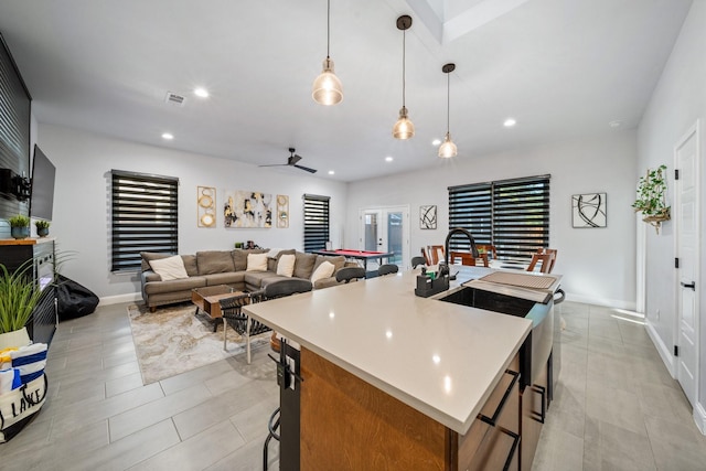 kitchen with a center island with sink, pendant lighting, a breakfast bar area, and ceiling fan