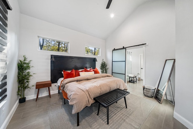 bedroom featuring a barn door, ceiling fan, and high vaulted ceiling