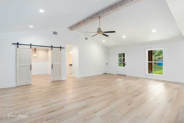 unfurnished living room with vaulted ceiling with beams, ceiling fan, a barn door, and light wood-type flooring