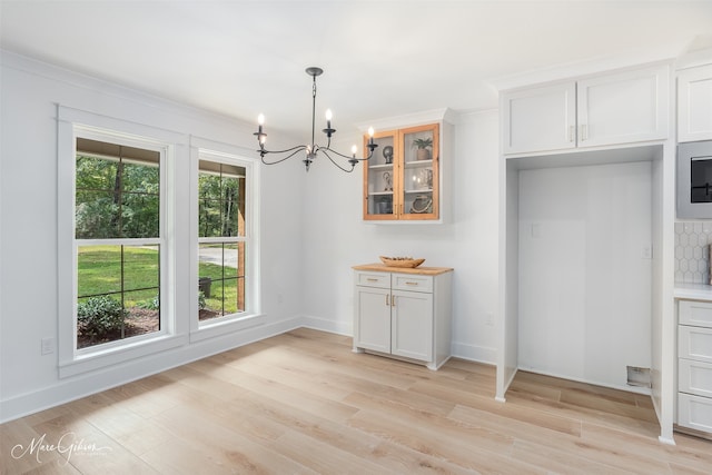 251 Jessie Jones Dr, Benton, LA 71006 - unfurnished dining area with light wood finished floors, baseboards, and a notable chandelier