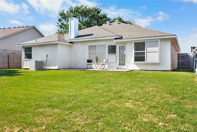 rear view of property featuring a fenced backyard, a chimney, cooling unit, and a lawn