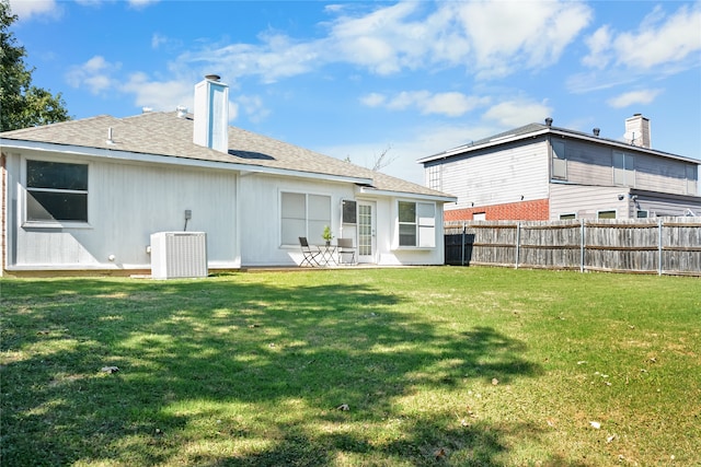 back of property featuring a yard, a chimney, fence, and central air condition unit