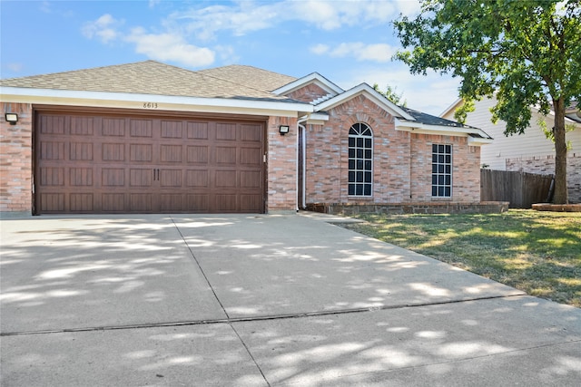 single story home with a garage, concrete driveway, brick siding, and fence