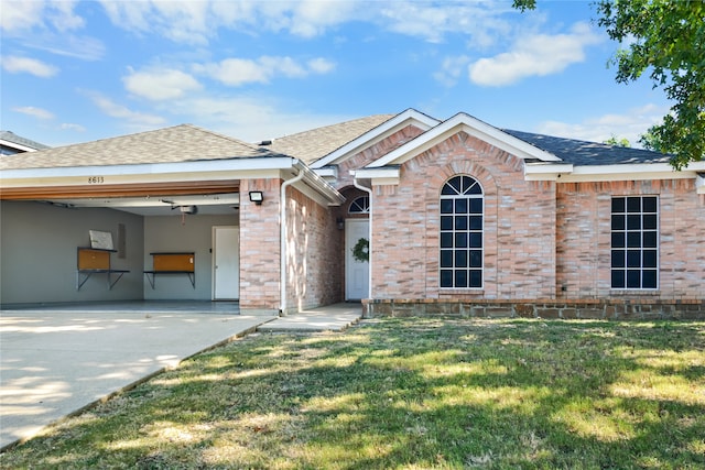 view of front facade with a garage, brick siding, a shingled roof, driveway, and a front yard