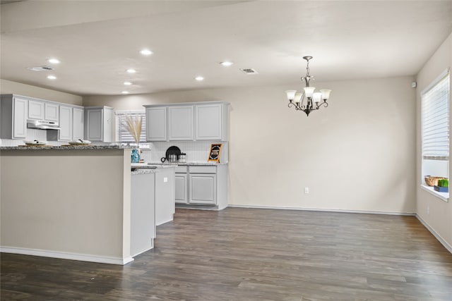 kitchen with tasteful backsplash, dark wood-style flooring, visible vents, and under cabinet range hood