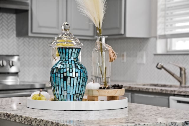 interior details featuring gray cabinets, a sink, electric range, and light stone countertops