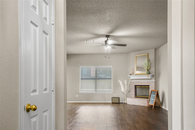 unfurnished living room featuring visible vents, dark wood-style floors, ceiling fan, a textured ceiling, and a brick fireplace