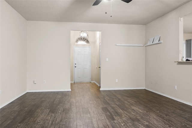 spare room featuring ceiling fan with notable chandelier, wood finished floors, and baseboards