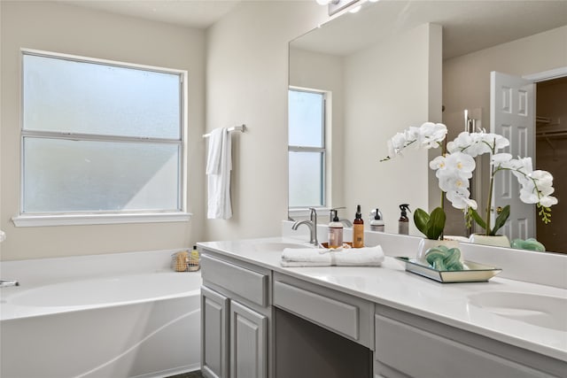 full bath with plenty of natural light, double vanity, a sink, and a bath