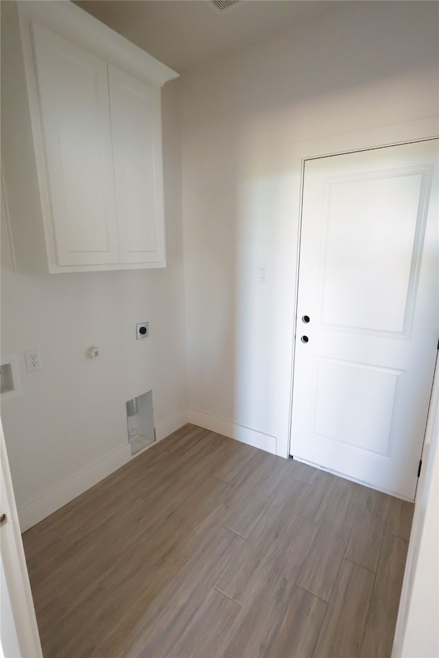 laundry room with cabinets, hookup for an electric dryer, gas dryer hookup, and light wood-type flooring