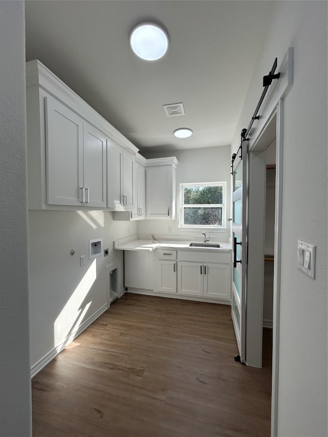 washroom with cabinets, sink, hookup for a washing machine, a barn door, and light hardwood / wood-style floors