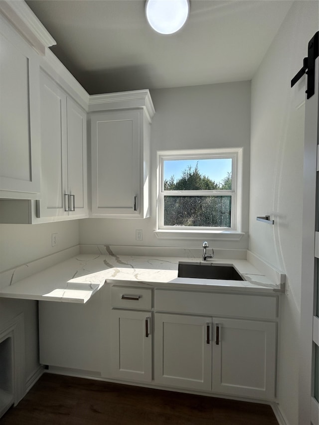 kitchen featuring light stone countertops, sink, white cabinets, and dark wood-type flooring