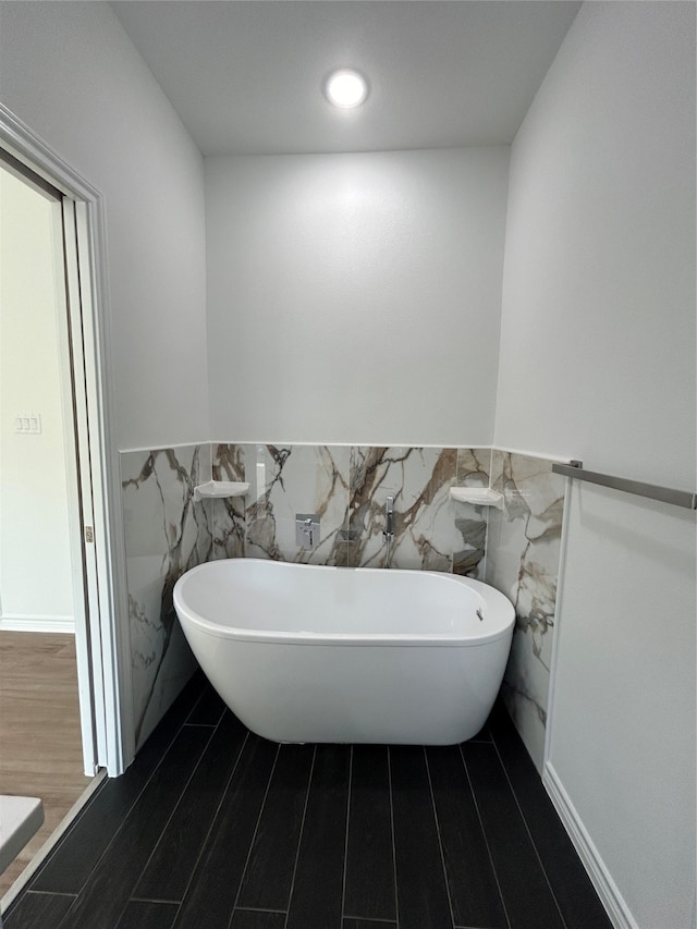 bathroom featuring hardwood / wood-style floors, a bathtub, and tile walls