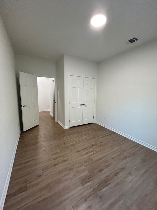 unfurnished bedroom featuring dark hardwood / wood-style flooring and a closet