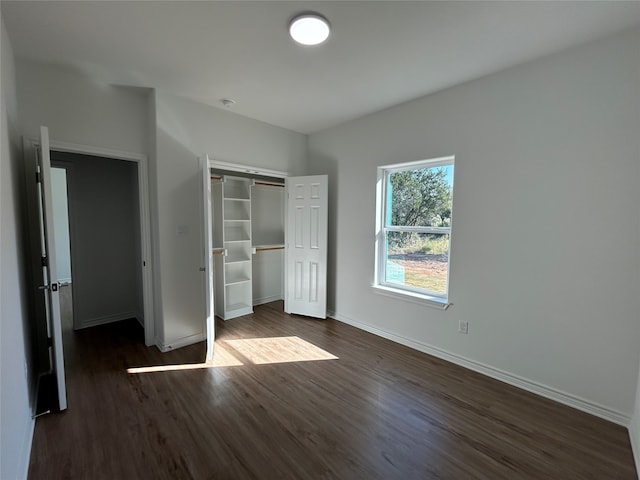 unfurnished bedroom with dark wood-type flooring and a closet