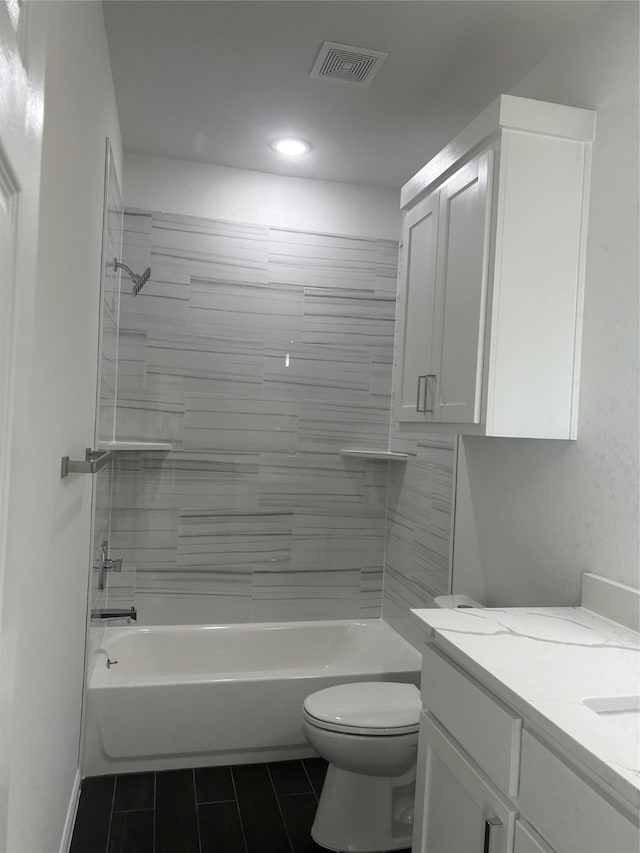 full bathroom with tile patterned floors, vanity, tiled shower / bath combo, and toilet