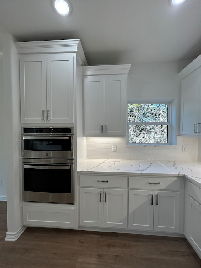 kitchen featuring backsplash, white cabinetry, dark wood-type flooring, and stainless steel double oven