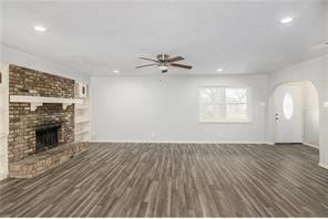 unfurnished living room with a fireplace, dark hardwood / wood-style floors, and ceiling fan