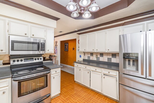 kitchen with light parquet flooring, backsplash, white cabinetry, stainless steel appliances, and ornamental molding