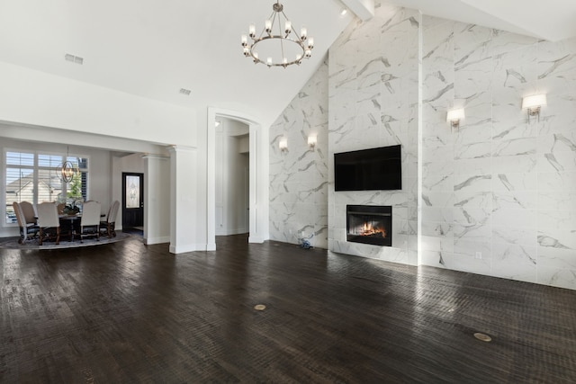 unfurnished living room featuring ornate columns, wood-type flooring, a high end fireplace, lofted ceiling with beams, and tile walls