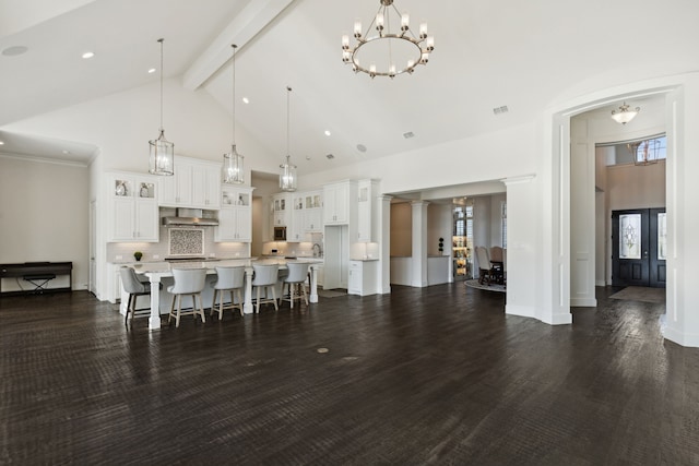 kitchen with white cabinets, a spacious island, dark wood-type flooring, wall chimney exhaust hood, and decorative light fixtures