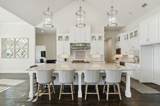 kitchen with wall chimney exhaust hood, white cabinetry, hanging light fixtures, and stainless steel microwave