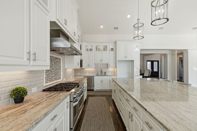 kitchen featuring white cabinetry, light stone countertops, stainless steel appliances, and decorative light fixtures