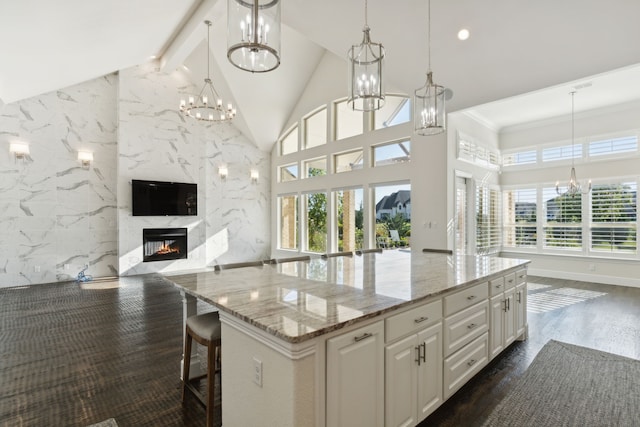 kitchen featuring light stone countertops, plenty of natural light, white cabinetry, pendant lighting, and dark hardwood / wood-style floors