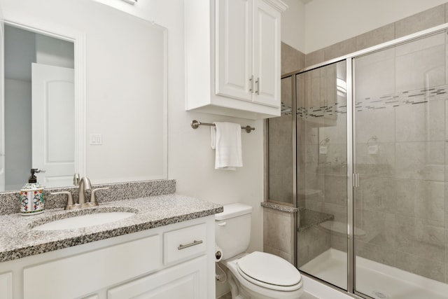 bathroom featuring toilet, a shower with shower door, and vanity