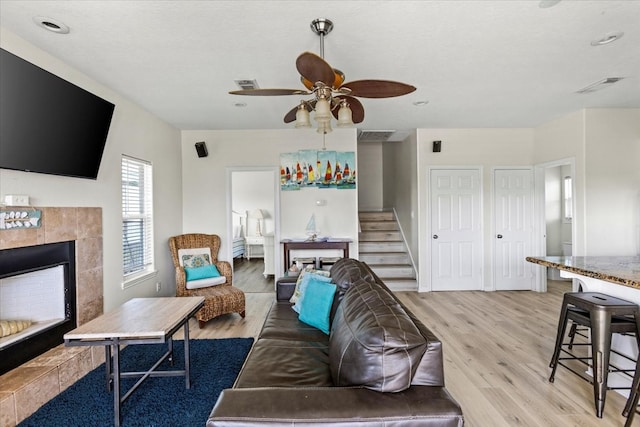 living room with ceiling fan, light hardwood / wood-style flooring, and a fireplace