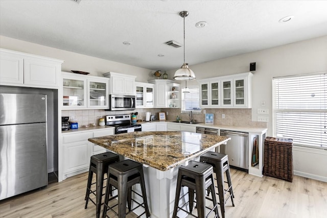 kitchen featuring white cabinetry, light hardwood / wood-style floors, stainless steel appliances, and a center island