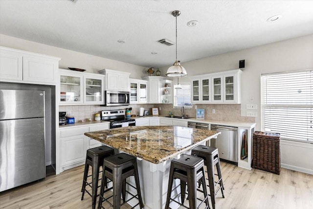 kitchen featuring light wood-style floors, a sink, decorative backsplash, and stainless steel appliances