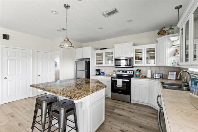 kitchen with a sink, appliances with stainless steel finishes, light wood-type flooring, and visible vents
