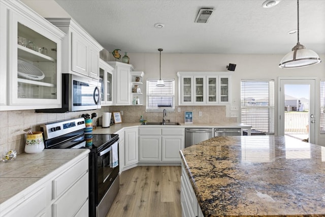 kitchen featuring hanging light fixtures, stainless steel appliances, sink, light wood-type flooring, and white cabinetry