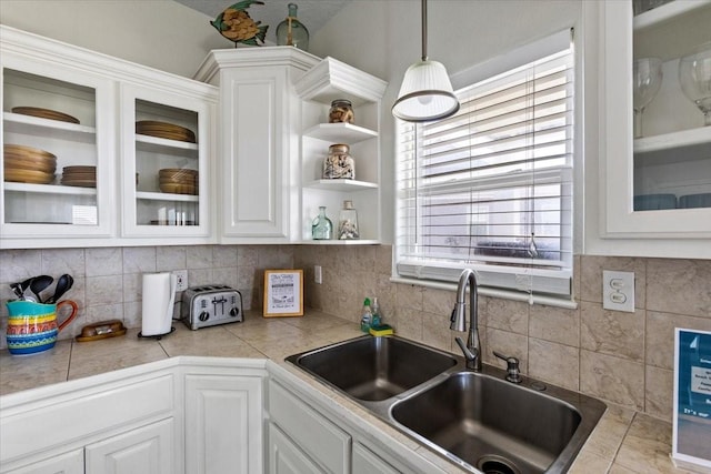 kitchen featuring white cabinets, glass insert cabinets, and a sink