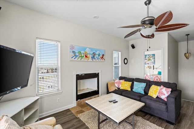 living room featuring a ceiling fan, baseboards, dark wood finished floors, and a healthy amount of sunlight