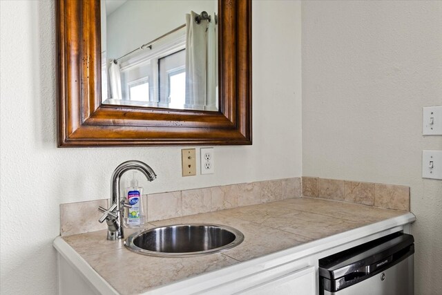 kitchen featuring stainless steel dishwasher, sink, and white cabinetry